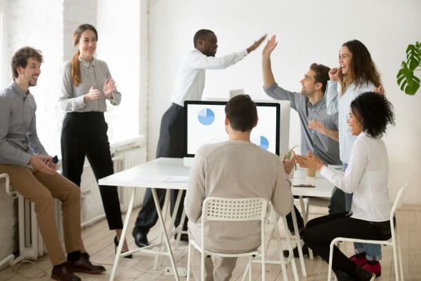 group of happy people looking at computer with marketing report