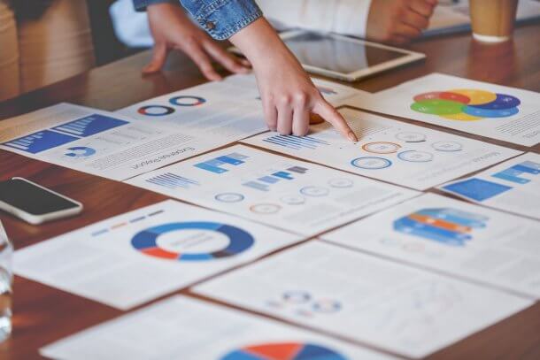 hands pointing at marketing reports printed on paper sheets