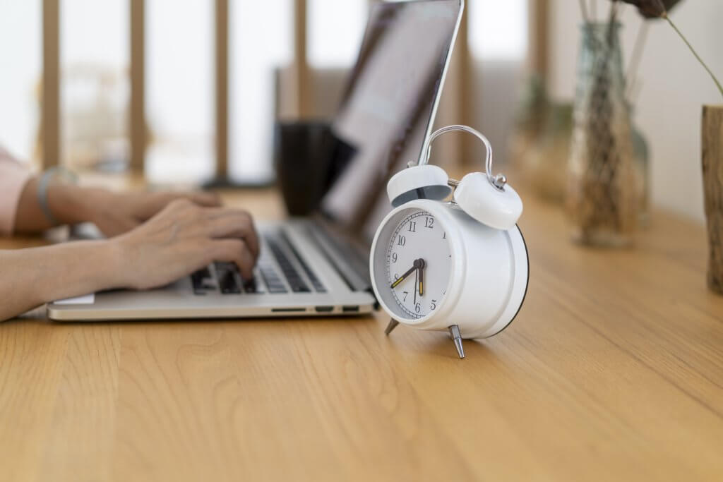 The alarm clock on the desk and the laptop