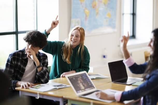 Teenagers raising hands in the class.