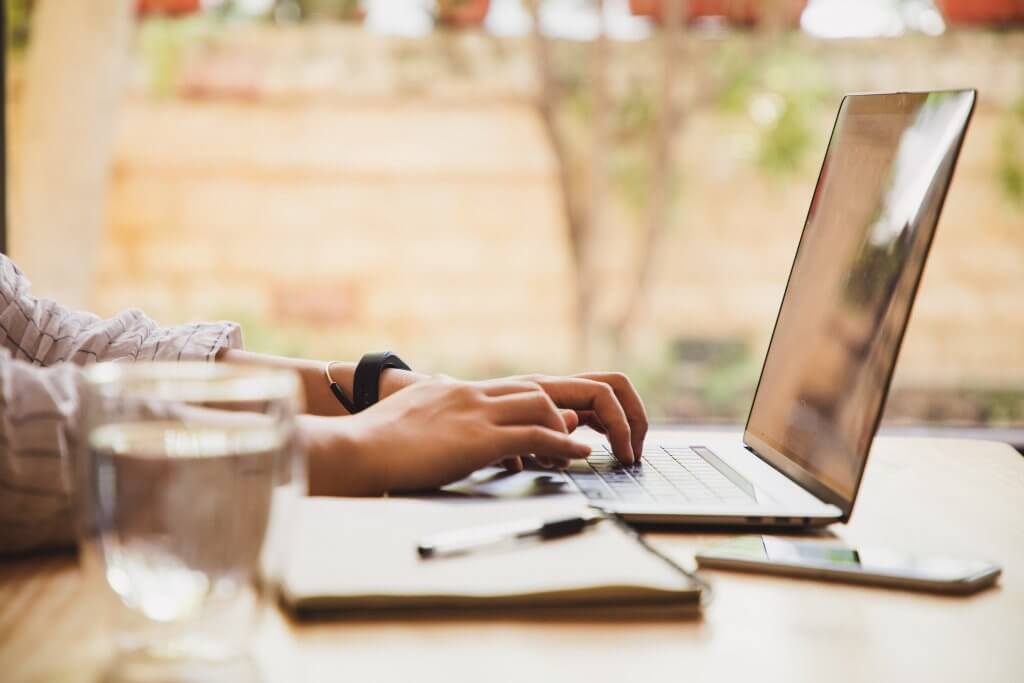 A woman writing on her laptop at home, creating a sales report.