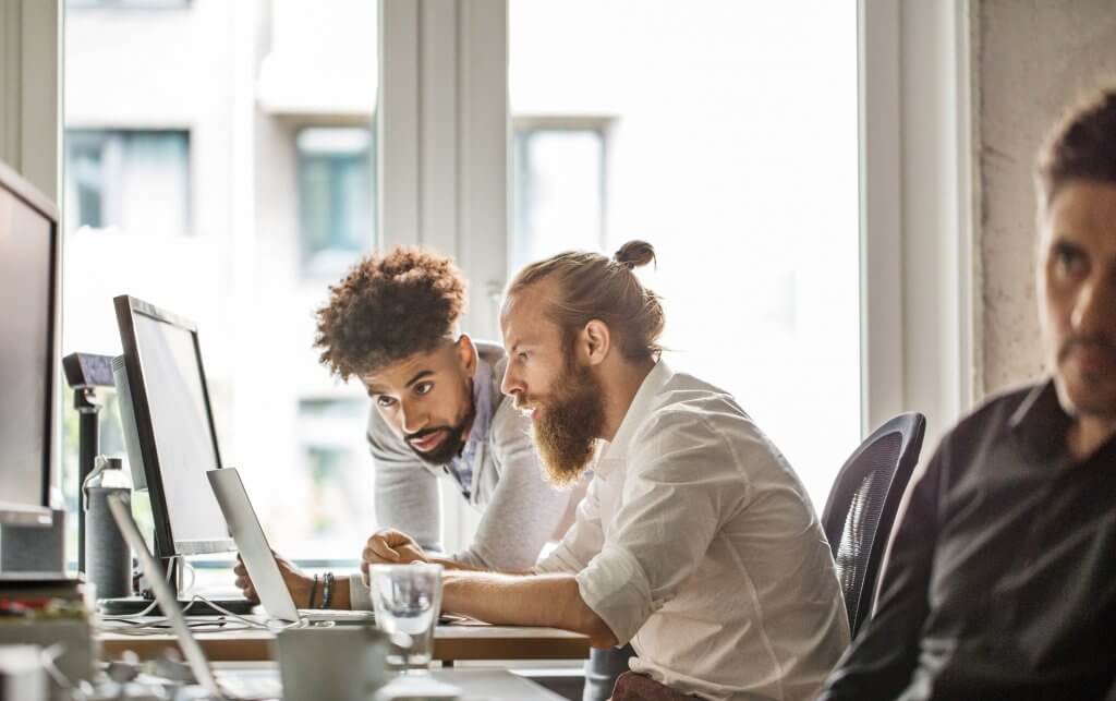 Multi-ethnic businessmen discussing over laptop in office