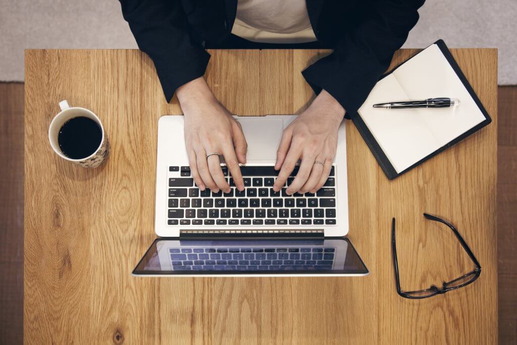 Overhead view of man working on laptop at cafe.