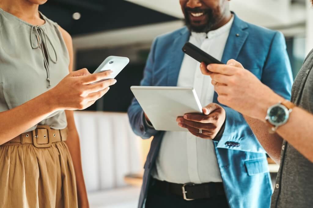 Diversity in work team using internet on phones and digital tablet for teamwork growth in the office. Professional staff work with 5g technology to match work schedule online the company website