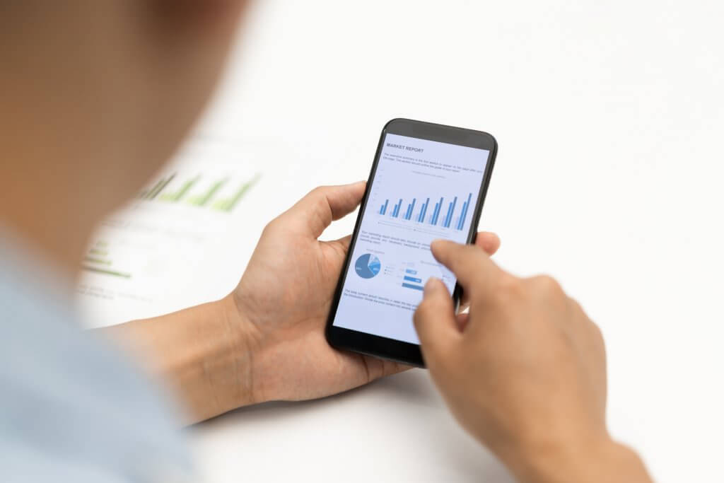 Closeup shot of a businessman analyzing statistics on a smart phone in an office