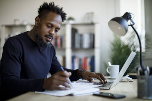 Man working at home, writing different types of reports.