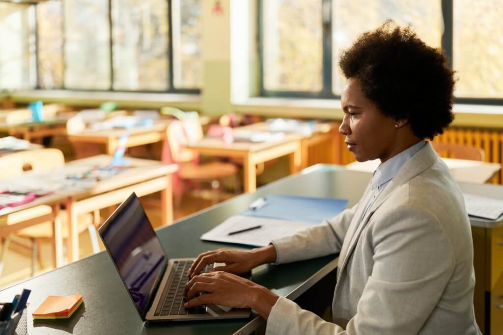 African American female teacher working on a computer at elementary school.