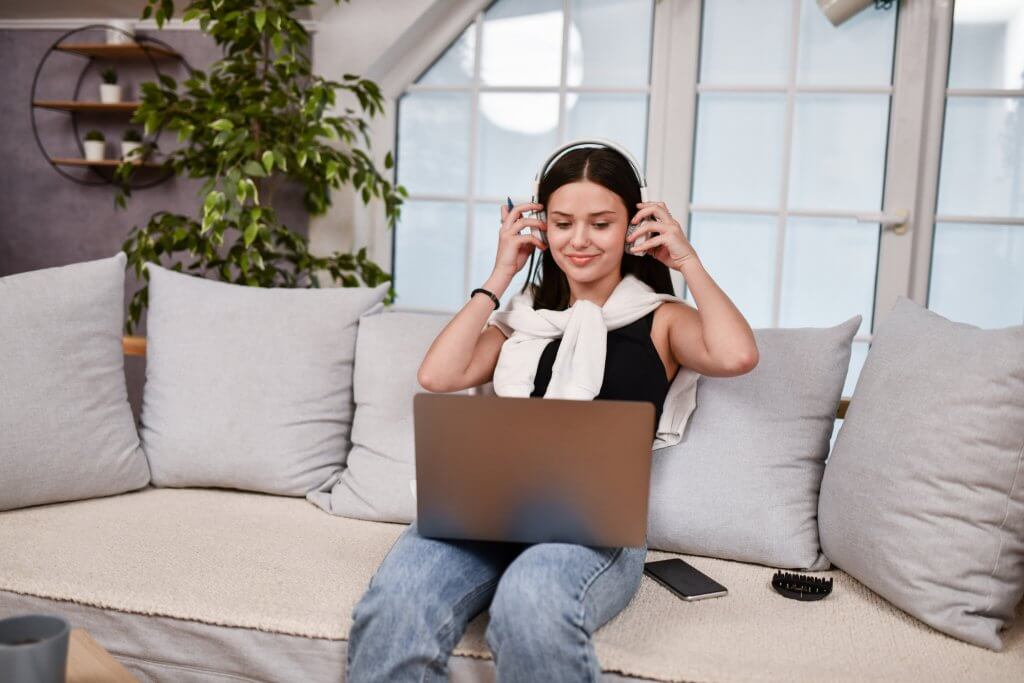 Female Putting On Headphones For Online Class