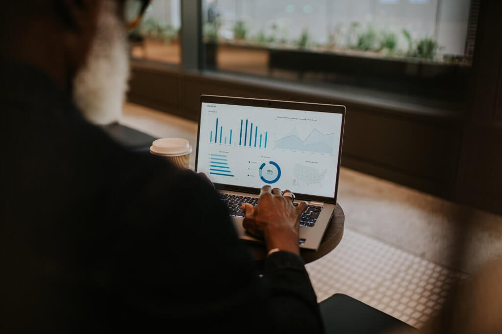 Focus on a laptop screen. A man uses a laptop and looks at financial figures, including graphs and charts.