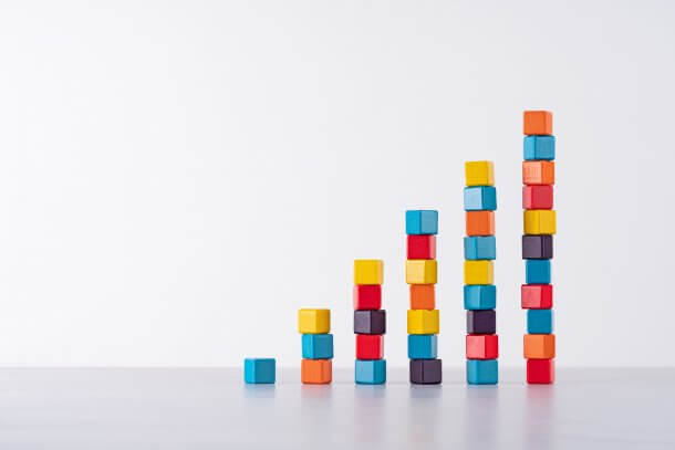 Colorful Lacquered Wooden Blocks Stack Bar Graph Moving up on Bright White Gray Background.