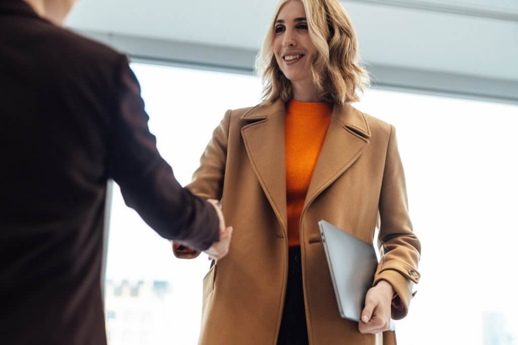 Low angle view of successful female estate agent sealing a sales deal with her client with handshake. Real estate industry. Diversity, Equity and Inclusion in the workplace.