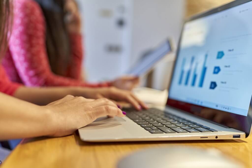 only hands two young women working in the office on their laptop devices unfocused background