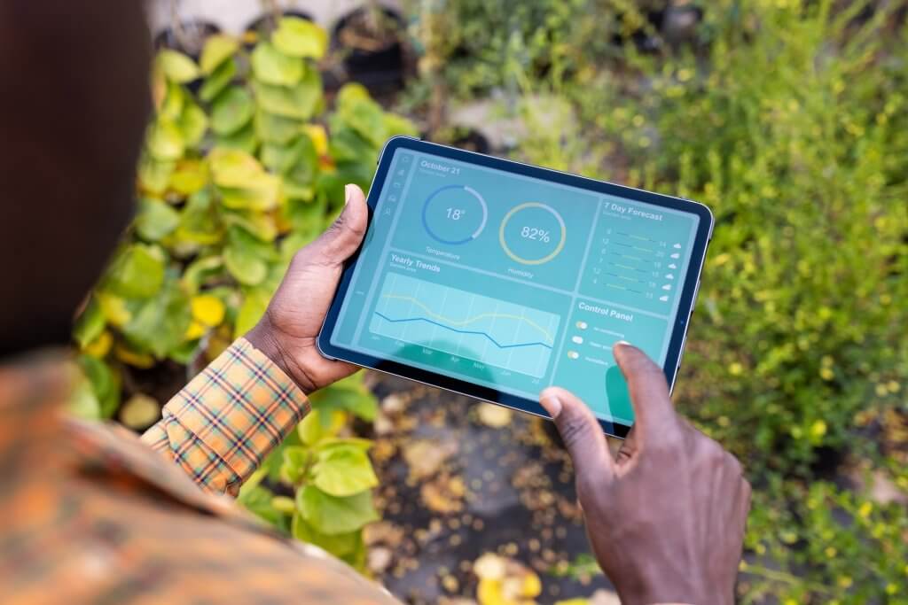 Cropped shot of a male agronomist using digital tablet for analysis of planted trees. Man updating plants growth on digital tablet app in garden center.